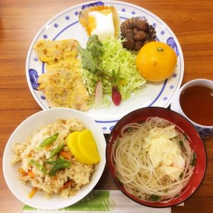 ポークピカタや炊き込みご飯、素麺のお汁などが並ぶ昼食